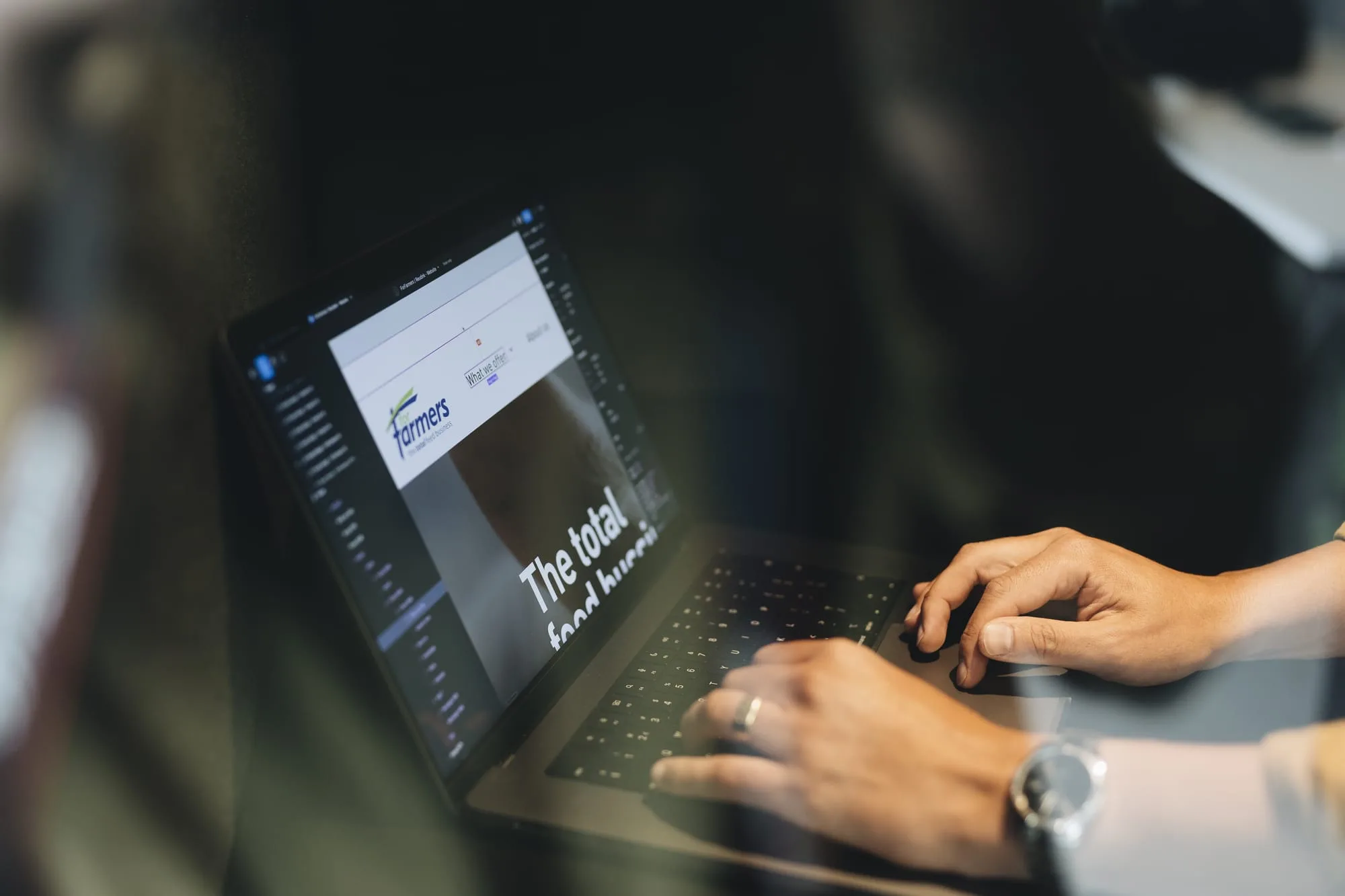 Op de afbeelding is een laptop te zien met een pagina open. Daarnaast zijn er ook handen weergegeven.