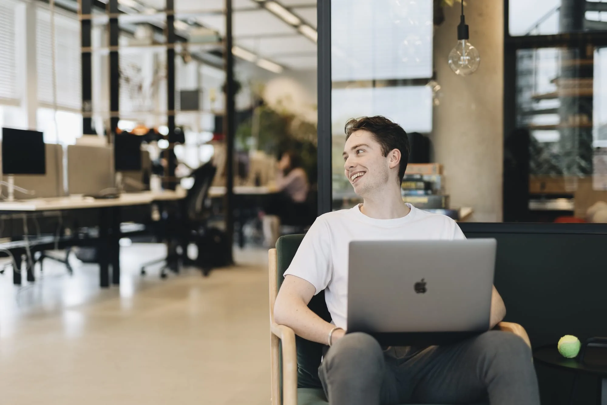 Jairo glimlacht en heeft een laptop op schoot.